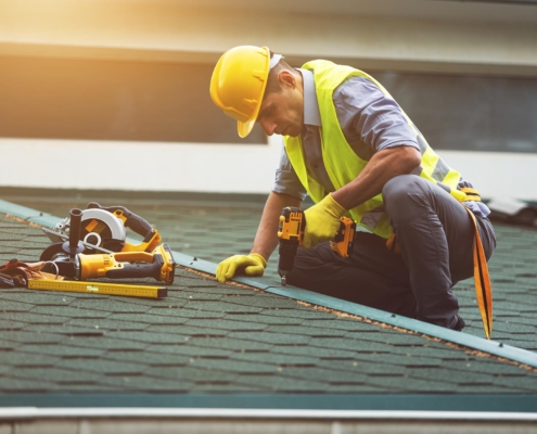 Worker redoing roof of commercial building Insurance roof replacement