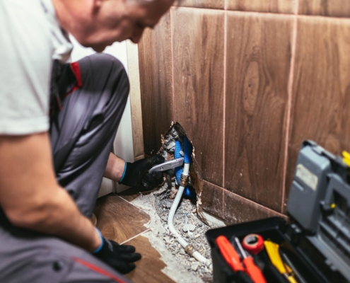 Worker running new water pipes through the floor